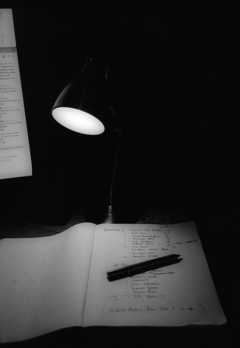 A desk lamp illuminating an open notebook.
